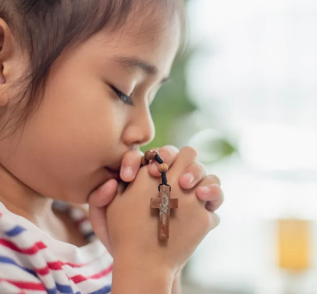 A young girl praying with a rosary