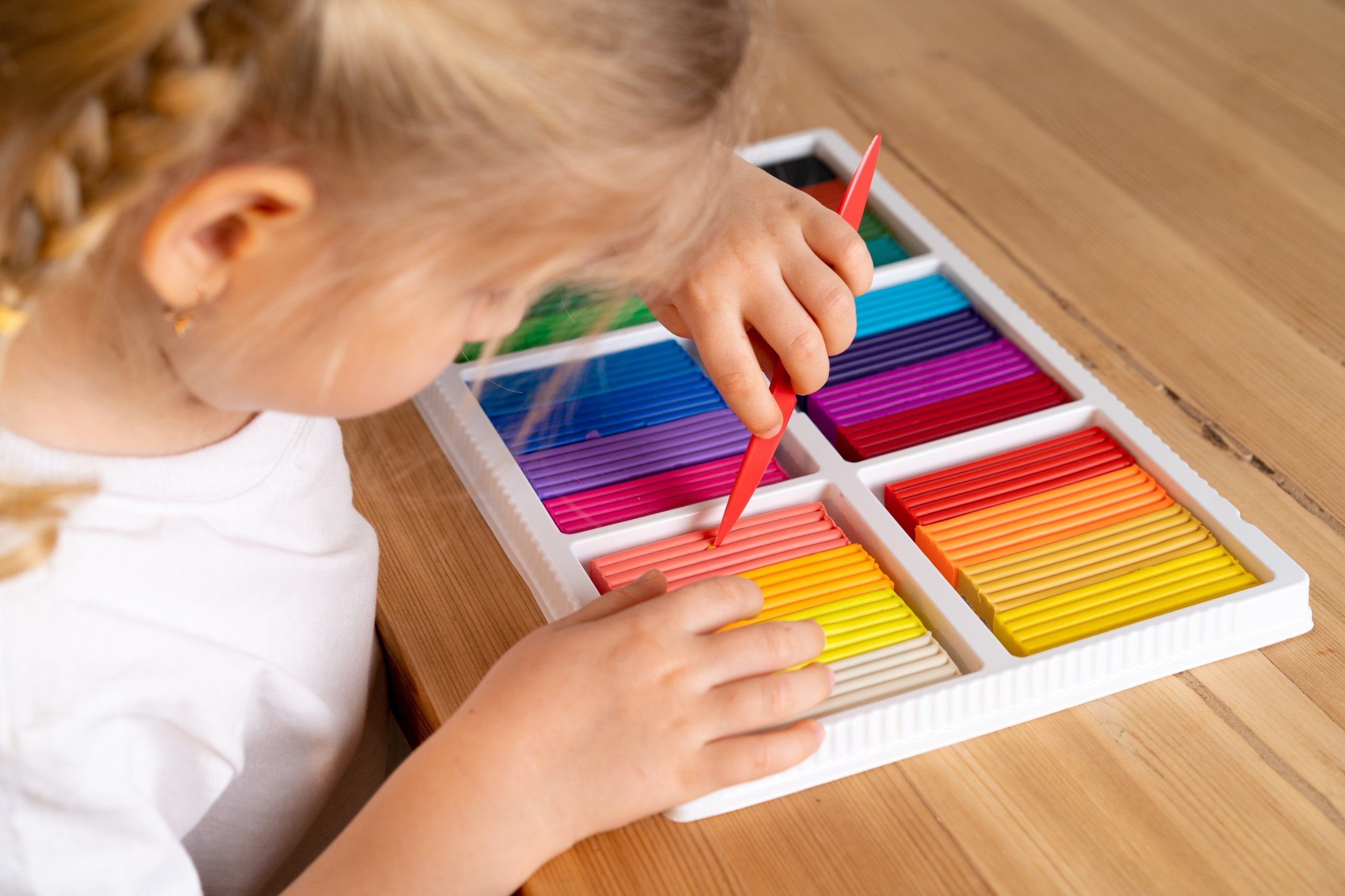 A child concentrating on a tray of colorful modeling clay