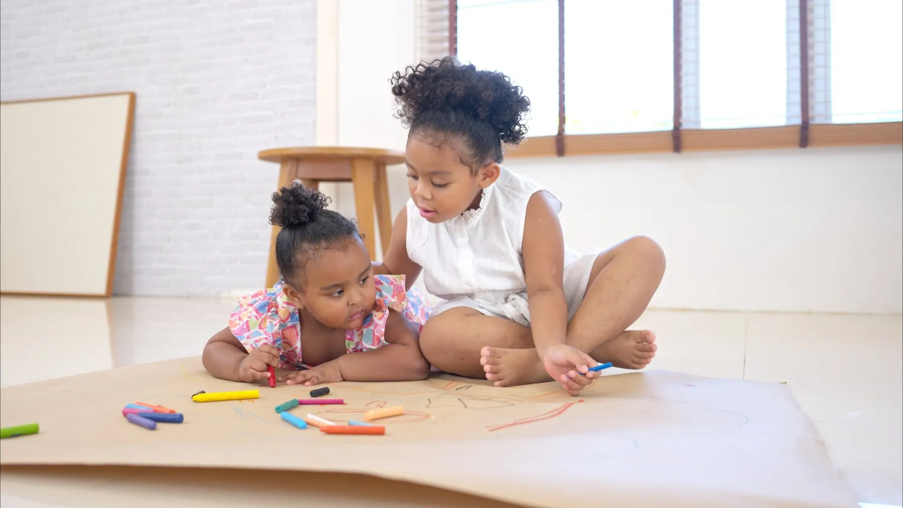 Two young children drawing side by side on the floor
