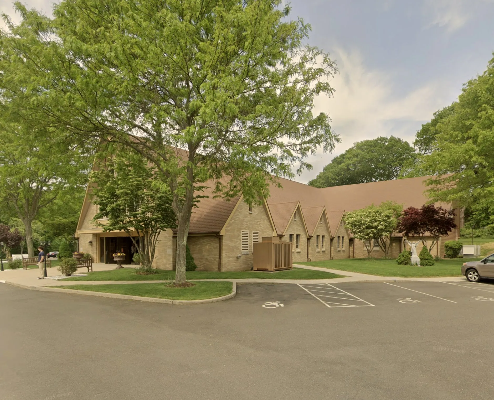 St. Lawrence Parish in Shelton, a brick church behind a large tree